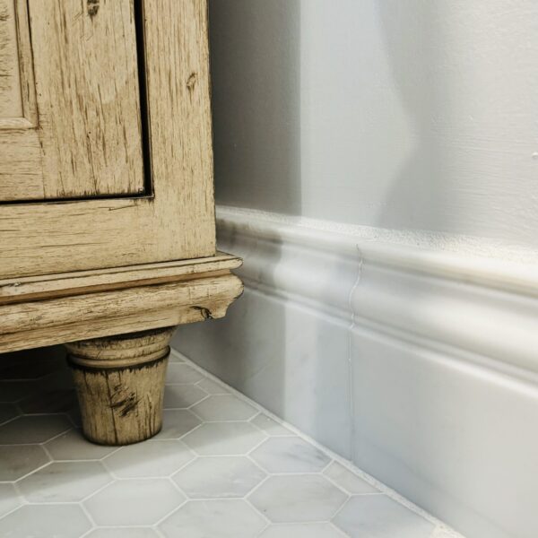 Detail photo showing the marble baseboard and foot of the vanity.